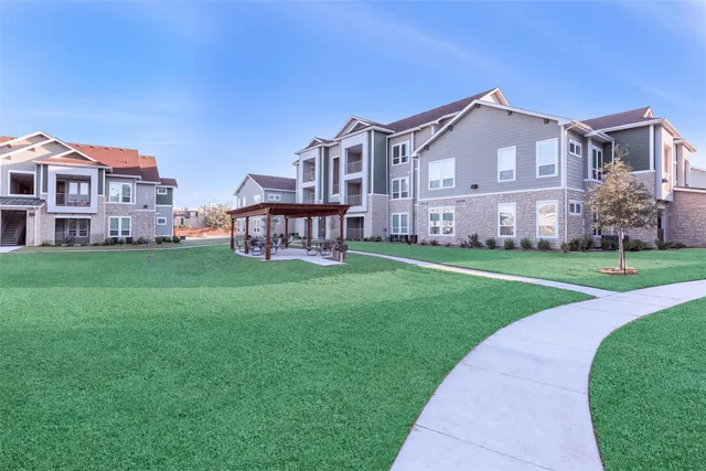 a view of a big house with a big yard and large trees