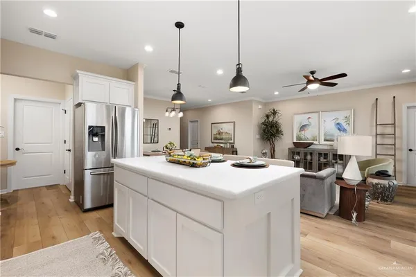 a kitchen with stainless steel appliances a stove a sink a refrigerator a center island a stove and a refrigerator with white cabinets