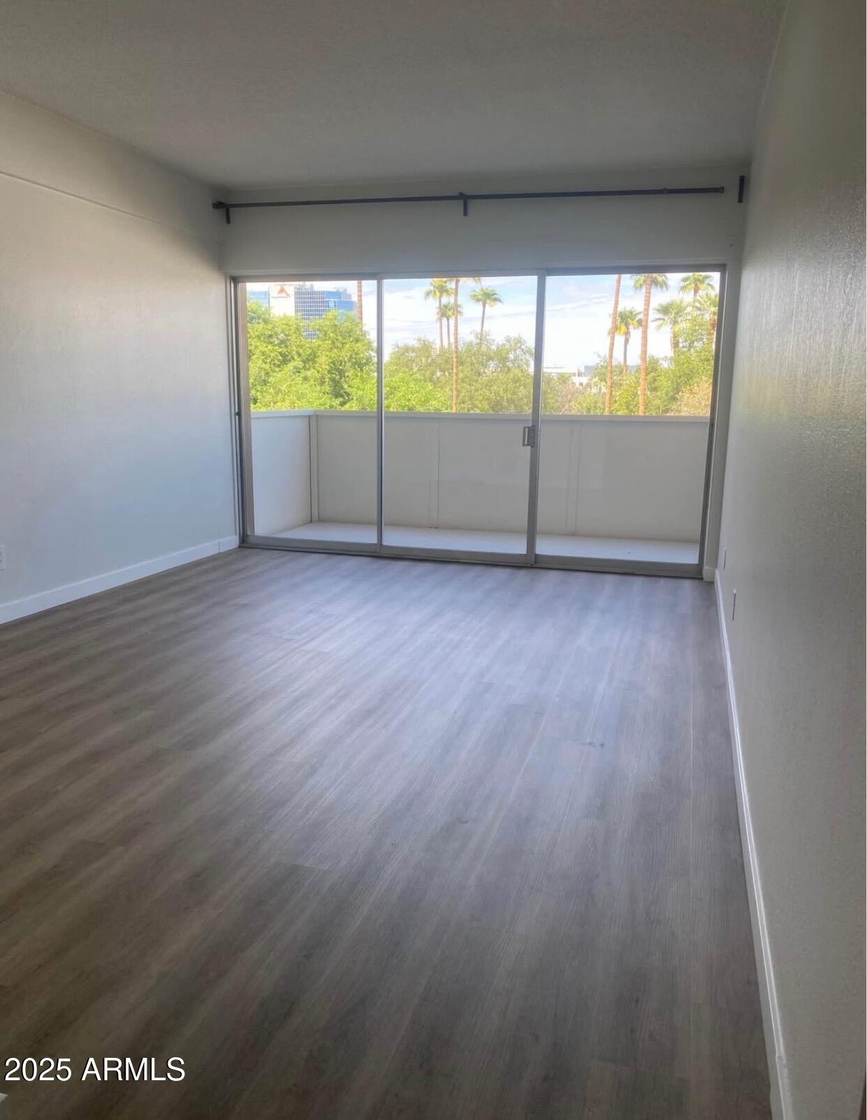 353 East Thomas Road, Unit C404 Phoenix, AZ 85004 - Photo 4 of 18 an empty room with wooden floor and windows