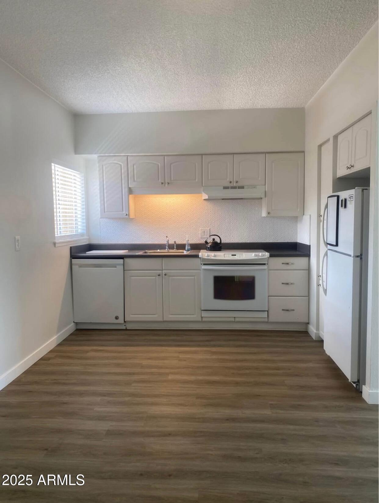 353 East Thomas Road, Unit C404 Phoenix, AZ 85004 - Photo 5 of 18 a view of a kitchen with a stove wooden cabinets and entryway
