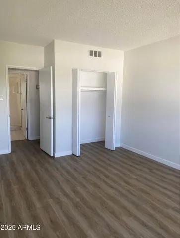 an empty room with wooden floor & closet area