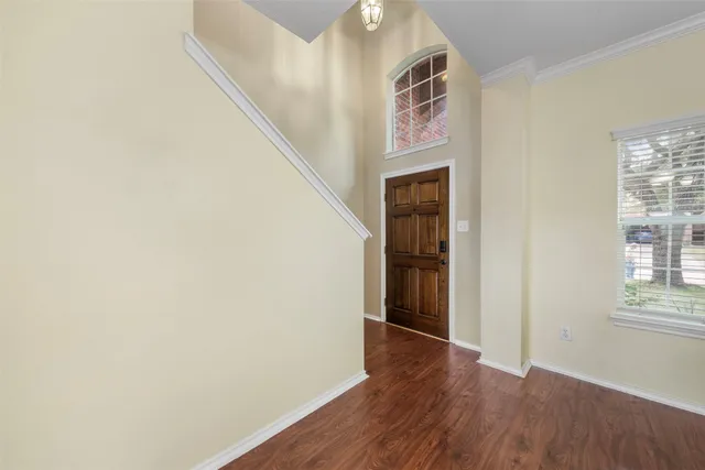 an empty room with wooden floor chandelier and windows