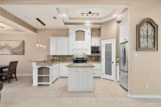 a large white kitchen with a stove a refrigerator and a fireplace