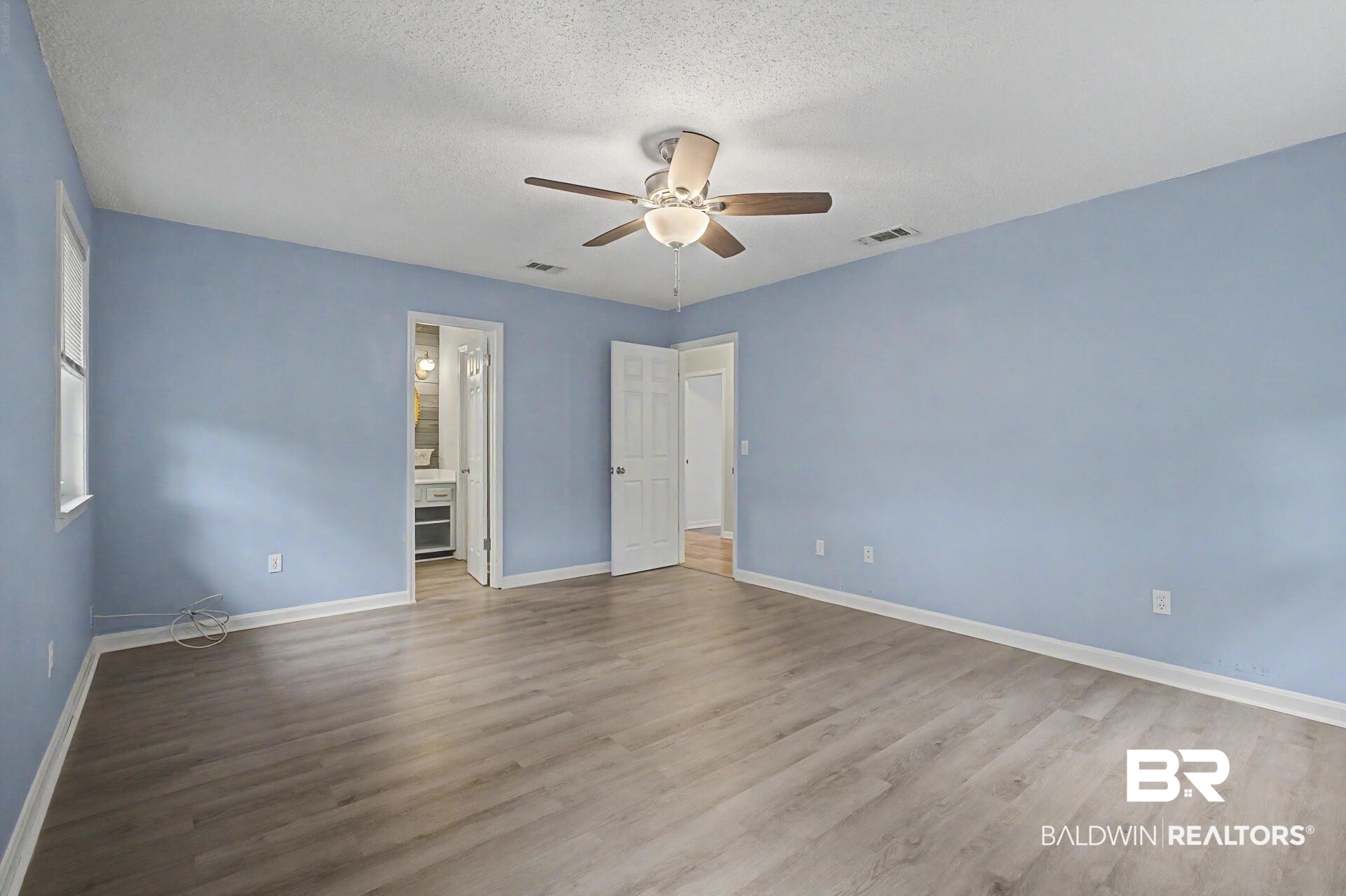 3791 Robinsonville Road Atmore, AL 36502 - Photo 44 of 47 Spacious room featuring wood-finish flooring, light blue walls, and a ceiling fan with integrated lighting