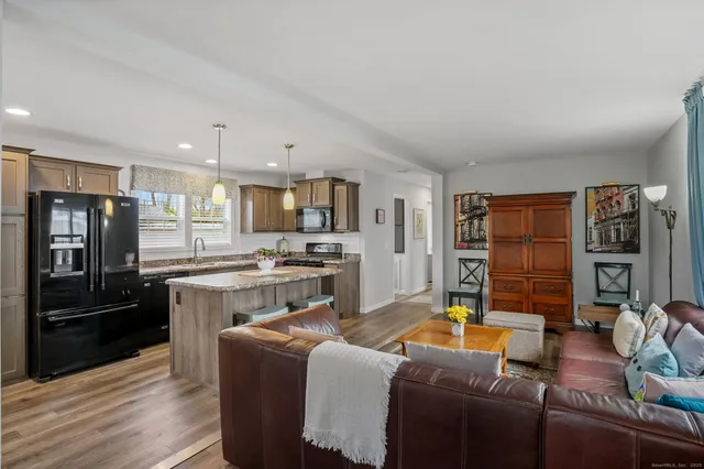 a living room with stainless steel appliances furniture and a kitchen view