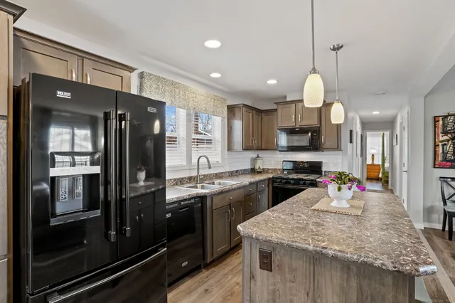 a kitchen with stainless steel appliances granite countertop a sink refrigerator and microwave