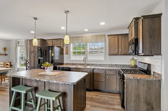 a kitchen with stainless steel appliances granite countertop a stove a sink a refrigerator and a wooden cabinets