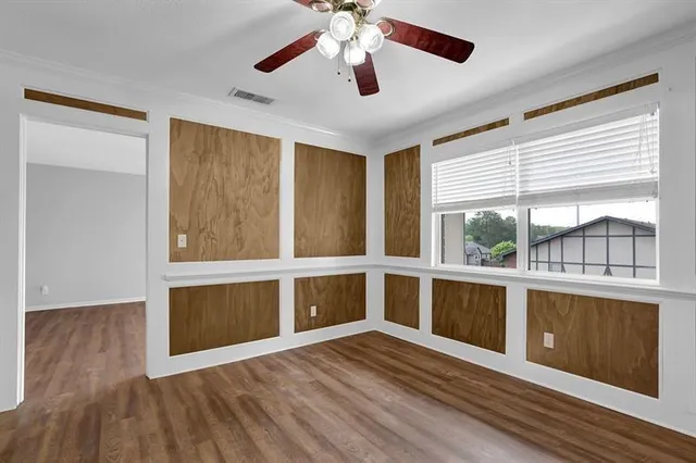 a view of an empty room with a window and wooden floor