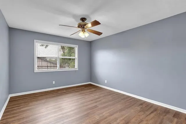 a view of an empty room with window and wooden floor