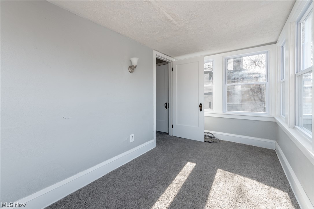 1228 Melbourne Road Cleveland, OH 44112 - Photo 23 of 35 Unfurnished room featuring dark carpet and a textured ceiling