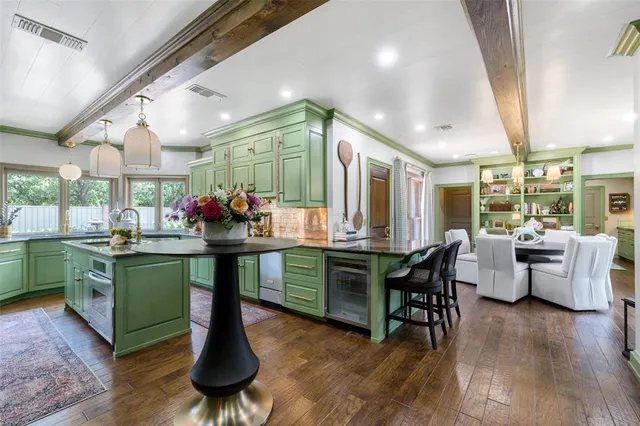 a kitchen with stainless steel appliances granite countertop dining table chairs and wooden floor