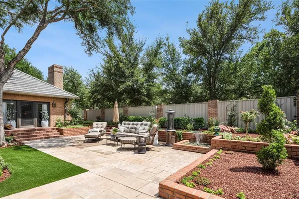 a view of a patio with table and chairs potted plants and large tree