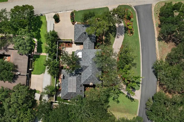 an aerial view of a house with outdoor space and trees all around