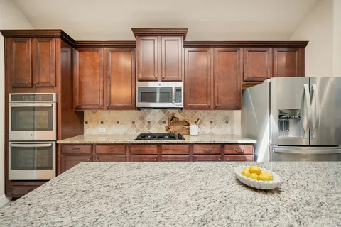 a kitchen with stainless steel appliances granite countertop a refrigerator and a stove top oven