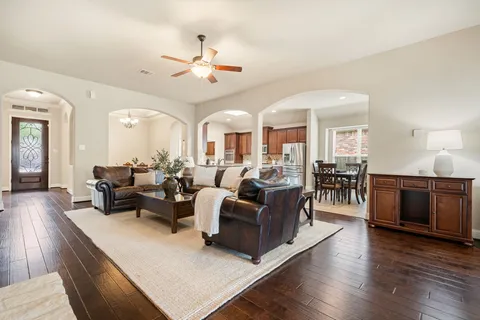 a living room with furniture kitchen view and a wooden floor
