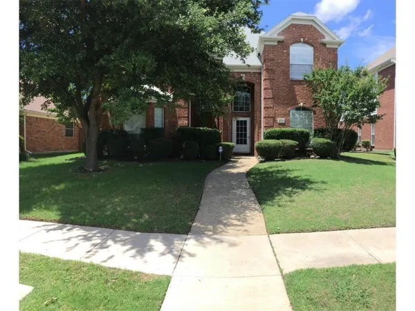 a backyard of a house with plants and large tree