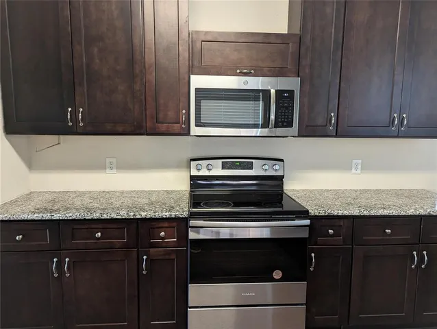 a kitchen with granite countertop wooden cabinets and a stove top oven