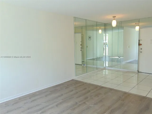 an empty room with wooden floor and mirror