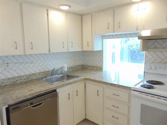 a kitchen with granite countertop white cabinets and a stove