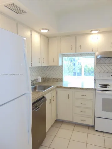 a kitchen with granite countertop white cabinets and white appliances