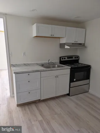 a kitchen with stainless steel appliances granite countertop a stove a sink and white cabinets