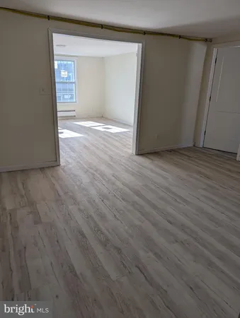 a view of an empty room with wooden floor and closet