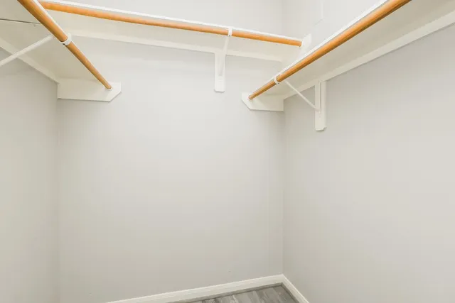 a view of an empty room with wooden floor and closet
