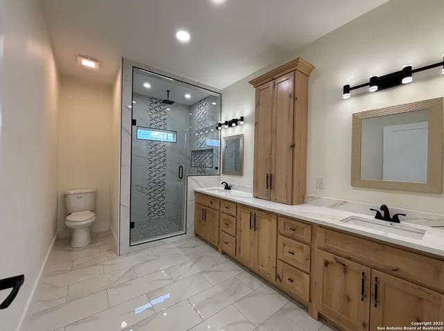 a spacious bathroom with a double vanity sink toilet mirror and bathtub