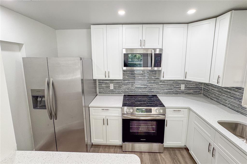 5436 East Michigan Street, Unit 4 Orlando, FL 32812 - Photo 8 of 37 a kitchen with stainless steel appliances granite countertop a stove a refrigerator and a microwave