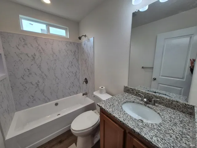 a bathroom with a granite countertop sink a toilet and bathtub