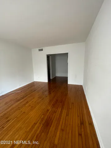 a view of an empty room with wooden floor