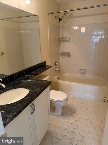a bathroom with a granite countertop bathtub sink vanity mirror and toilet