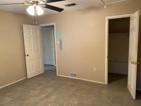 a view of an empty room and chandelier fan