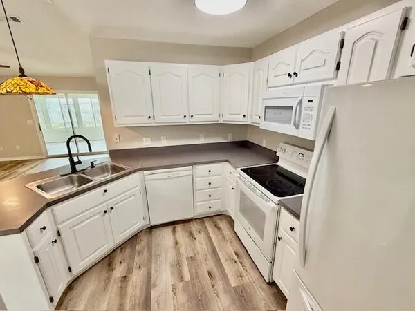a kitchen with granite countertop white cabinets and white appliances