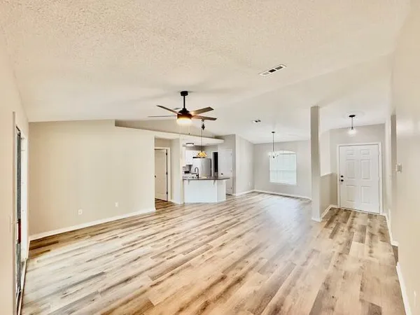 a view of a livingroom with a chandelier fan and wooden floor