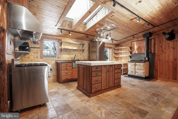 a kitchen with stainless steel appliances granite countertop a sink a stove and a wooden cabinets