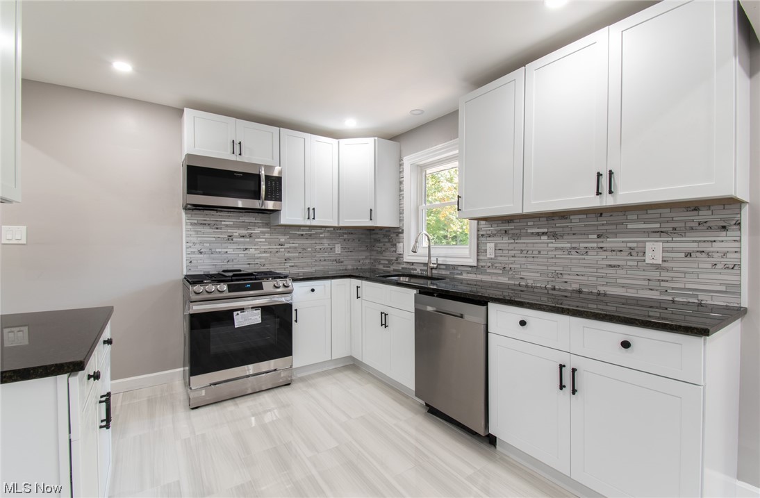 1097 South Meridian Road Youngstown, OH 44511 - Photo 7 of 29 Kitchen with sink, white cabinetry, dark stone countertops, tasteful backsplash, and appliances with stainless steel finishes