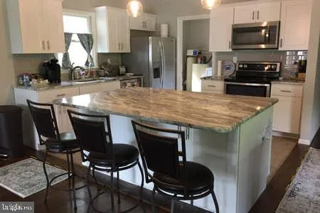 a kitchen with stainless steel appliances a kitchen island a stove a table and chairs in it