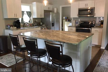 2605 Harrington Road Chester, MD 21619 - Photo 4 of 29 a kitchen with stainless steel appliances a kitchen island a stove a table and chairs in it