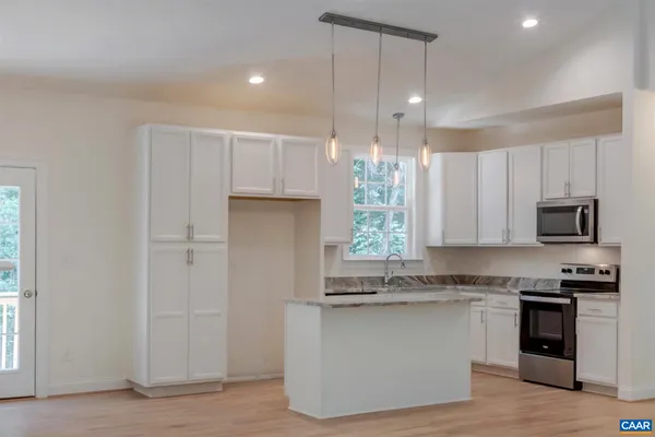 a kitchen with granite countertop a stove a sink and a refrigerator