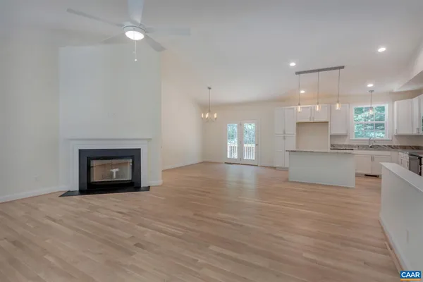 a view of an empty room and kitchen with wooden floor and a window