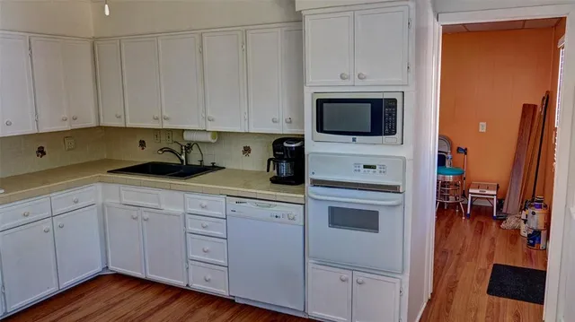 a kitchen with cabinets appliances a sink and wooden floor