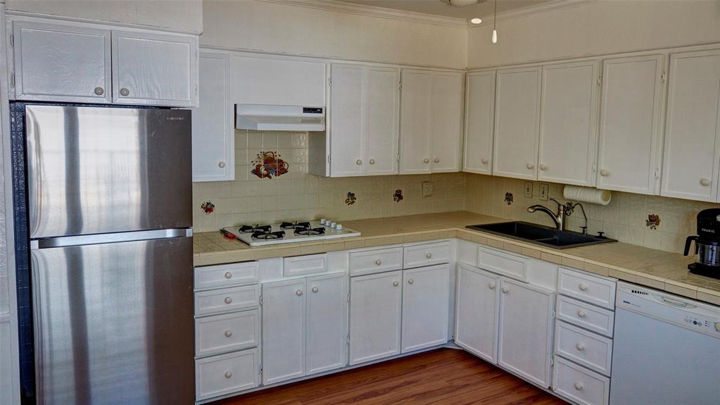 2612 West Rochelle Road Irving, TX 75062 - Photo 17 of 29 Kitchen featuring tile countertops, white appliances, white cabinetry, tasteful backsplash, and ornamental molding