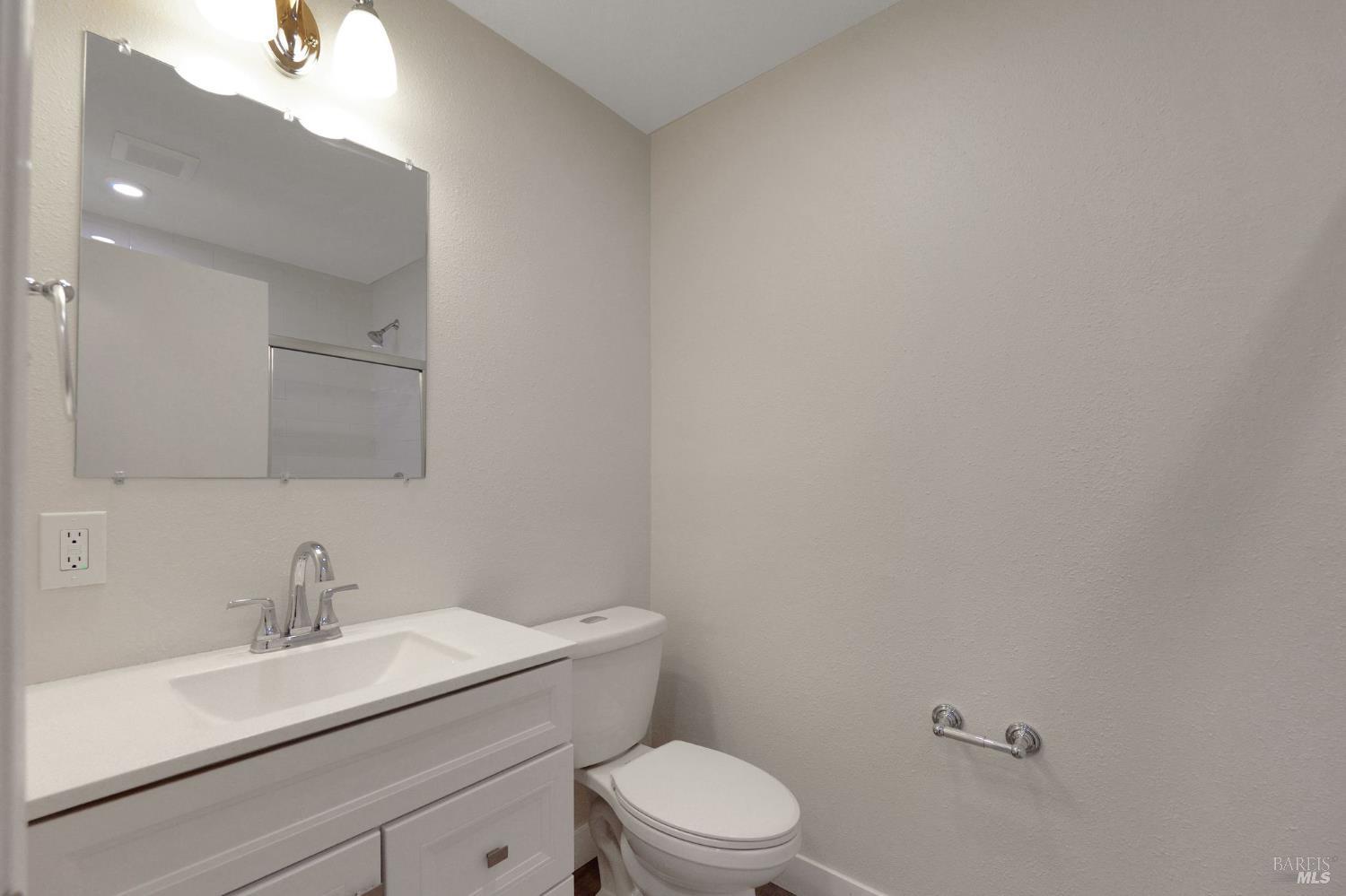 1120 Soda Canyon Road Napa, CA 94558 - Photo 19 of 38 a bathroom with a toilet a sink a mirror and vanity
