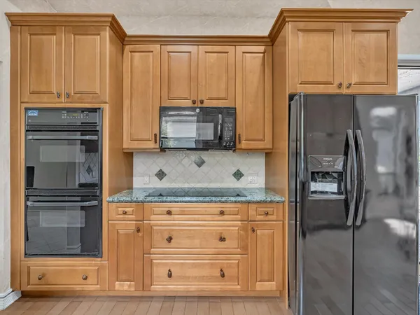 a kitchen with granite countertop a refrigerator and cabinets