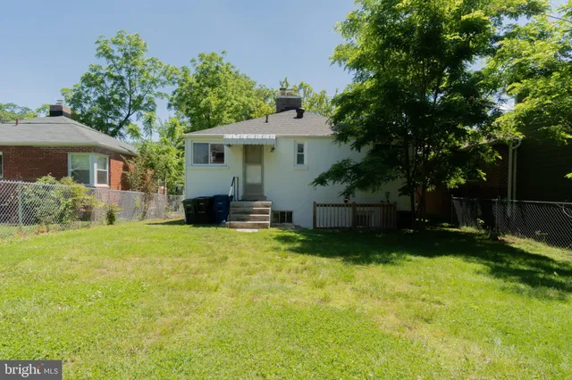 a view of a house with a yard and a large tree