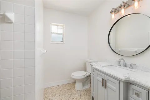 a bathroom with a granite countertop toilet a sink and a mirror