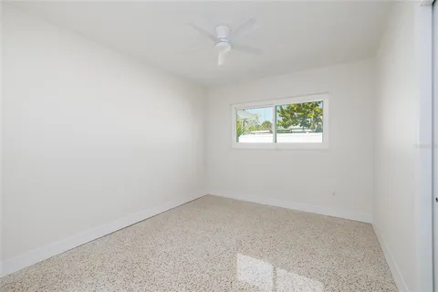 an empty room with windows and ceiling fan