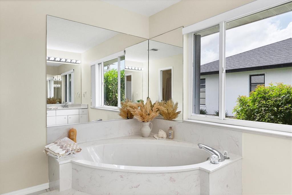 63 Clubhouse Road Rotonda West, FL 33947 - Photo 16 of 44 a bathroom with a tub a sink and a window