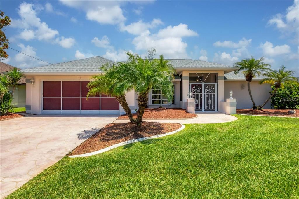 63 Clubhouse Road Rotonda West, FL 33947 - Photo 3 of 44 a front view of a house with a yard and potted plants